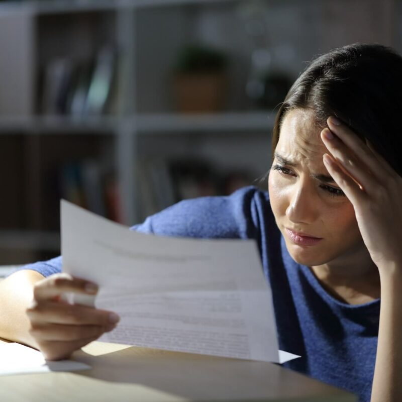 Concerned young woman looking at document 2